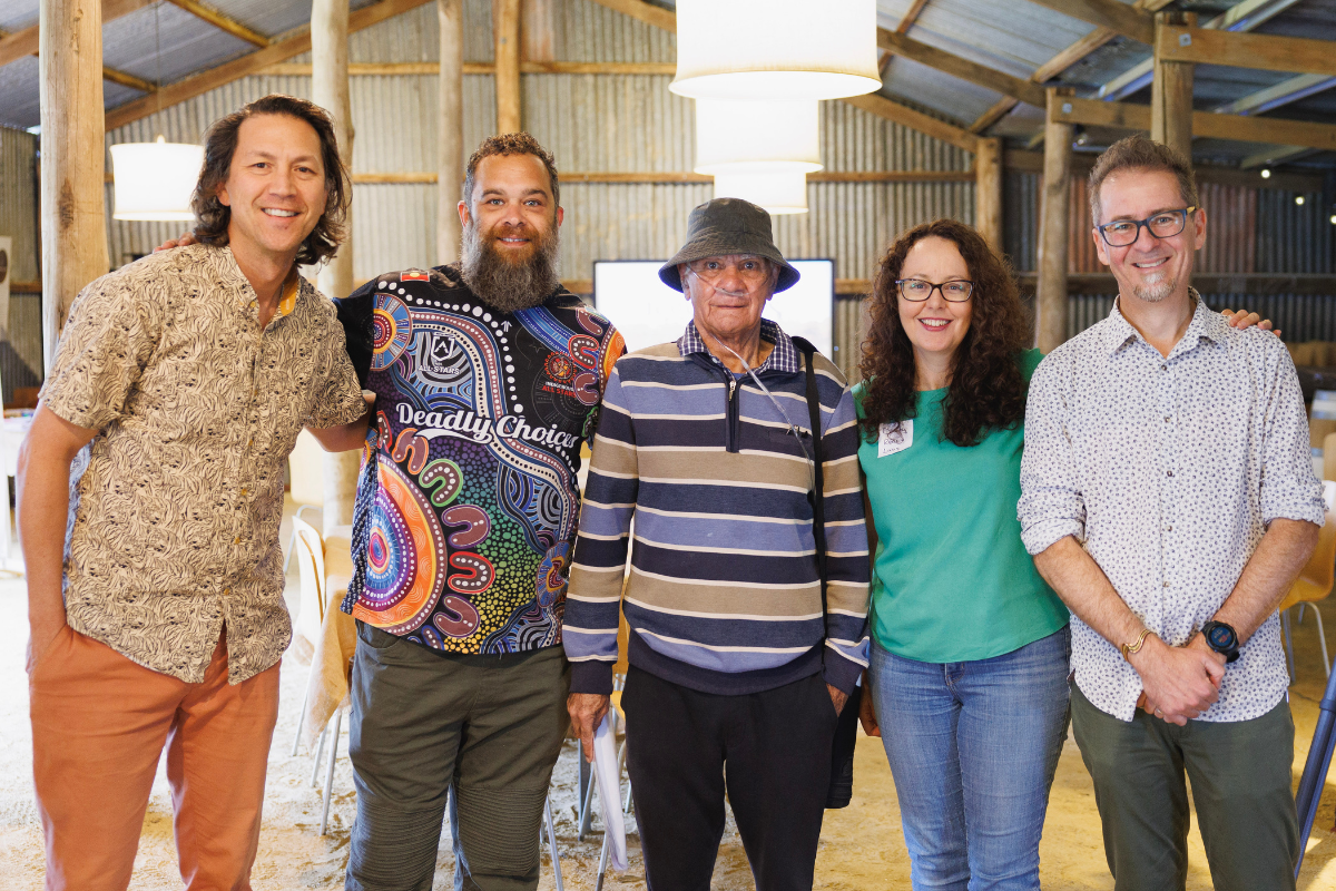 Five people standing side by side smiling at the camera in a rustic indoor setting, at the Regen Labs: WEAVE event.
